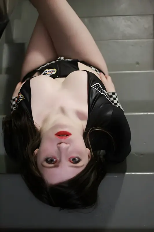 Em Ambisious lying upside down on wooden stairs in black lingerie and red lipstick